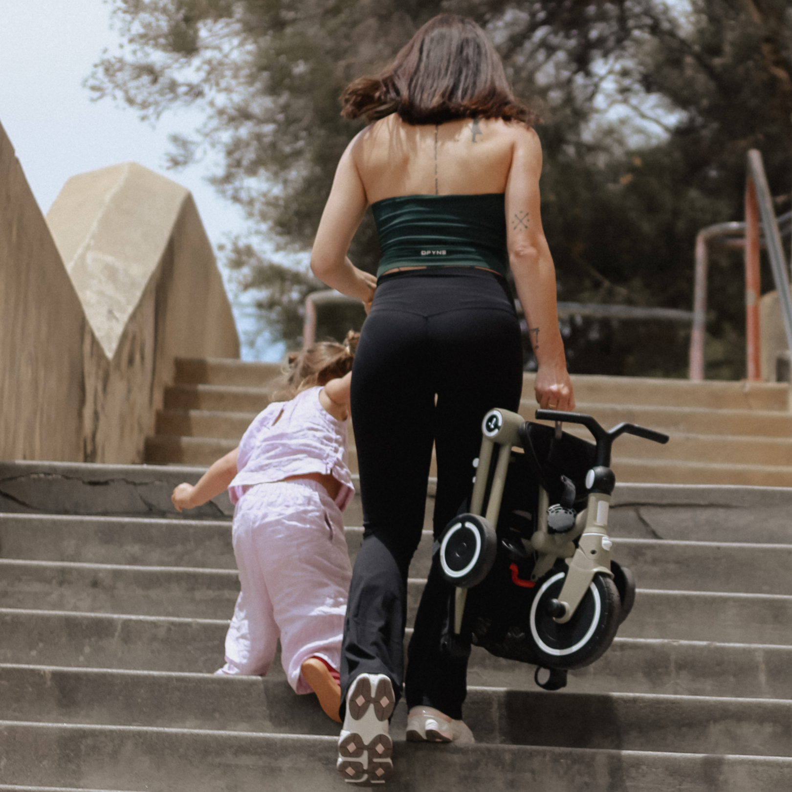 Parent carrying a folded Wonder up a flight of stairs